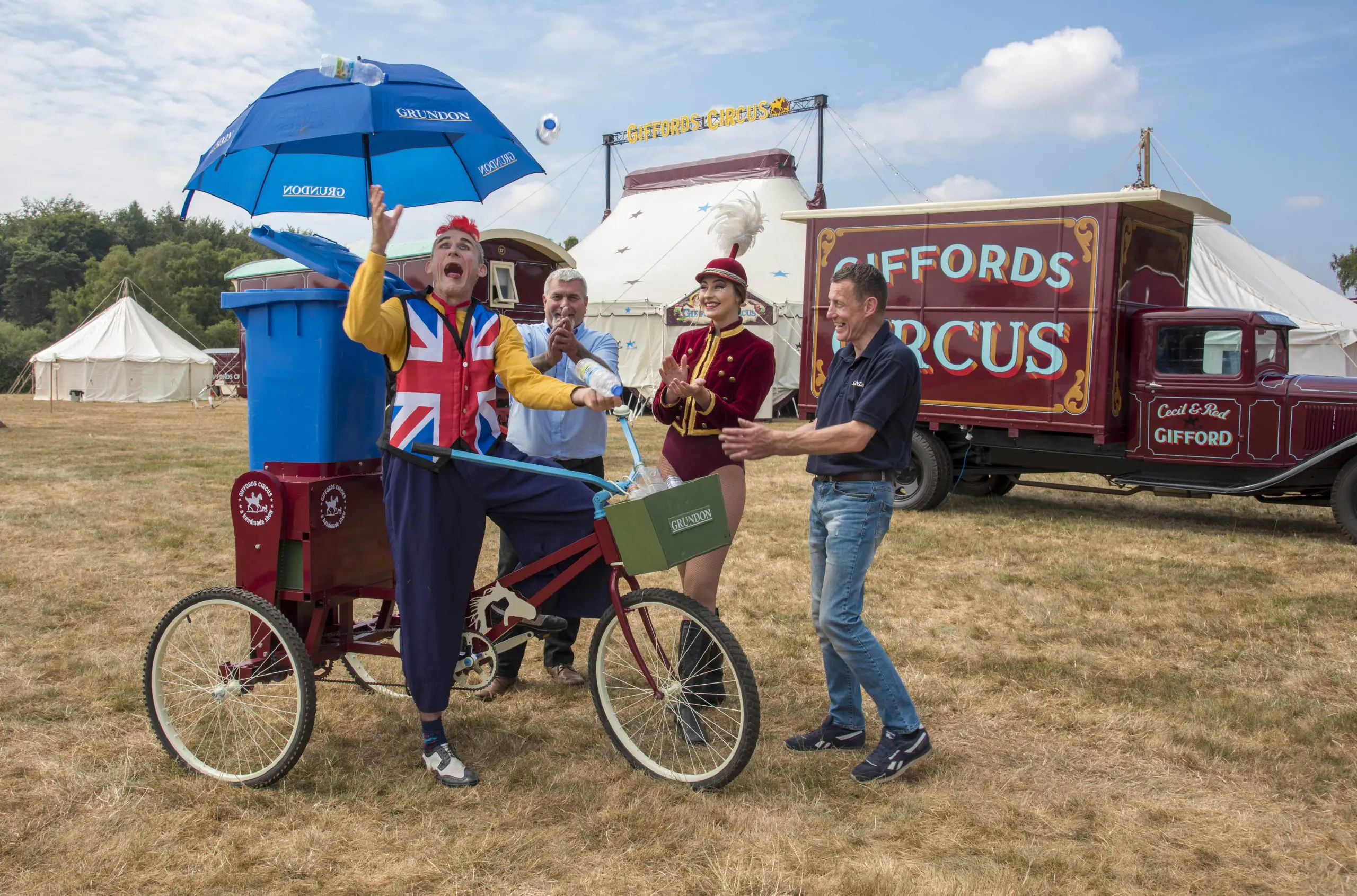 Tweedy shows off his juggling skills on the Recycle Bicycle watched by showgirl Lizzie and Grundon’s Peter Kent (left) and Dave Forrest