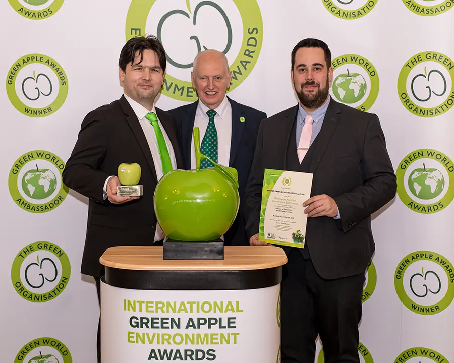 Forest Green Rover Football Club's General Manager, Dane Vince (left) and Daniel Peacey, Regional Sales Manager at Grundon Waste Management (right) collect the prestigious Gold Green Apple Award for Environmental Best Practice in the Sports Leisure & Hospitality wastes management category from Roger Wolens, Founder of The Green Apple Awards and Chief Executive Officer of The Green Organisation (centre)